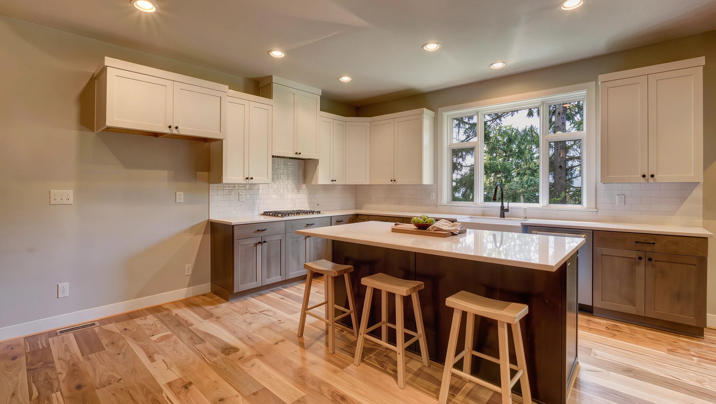 Remodeled kitchen with white shaker cabinets, quartz island and oak floors