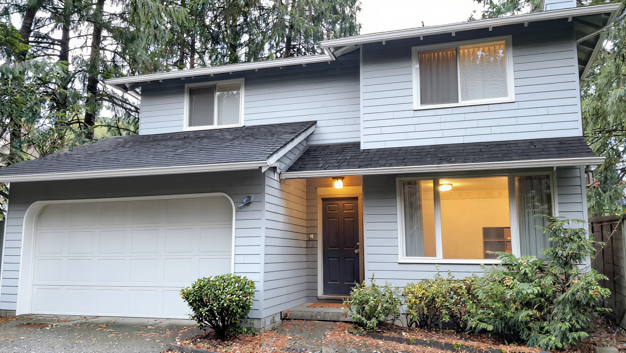 Two-story house with a new charcoal shingle roof and grey lap siding