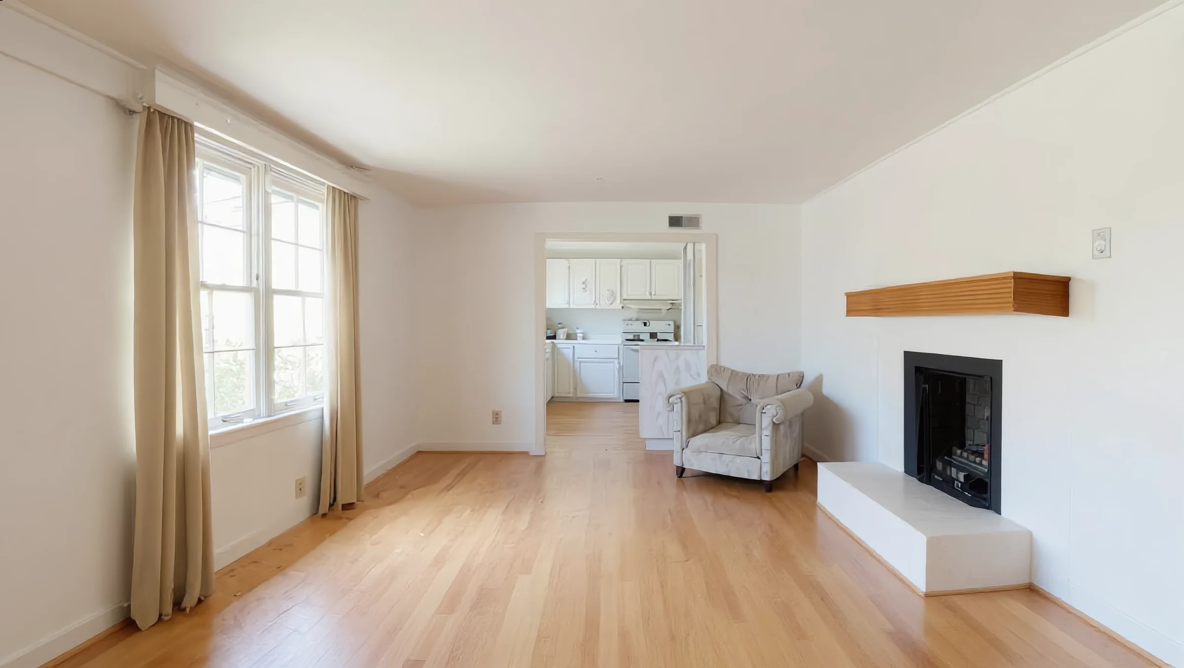 Renovated living room with white walls, oak floors and a refaced fireplace